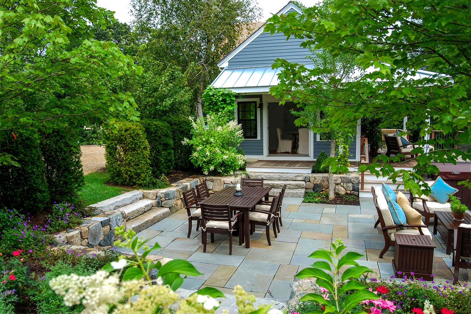 Wayland, MA - Garden patio with steps and privacy evergreens marries structured hardscape with lush planting for a tranquil outdoor retreat.