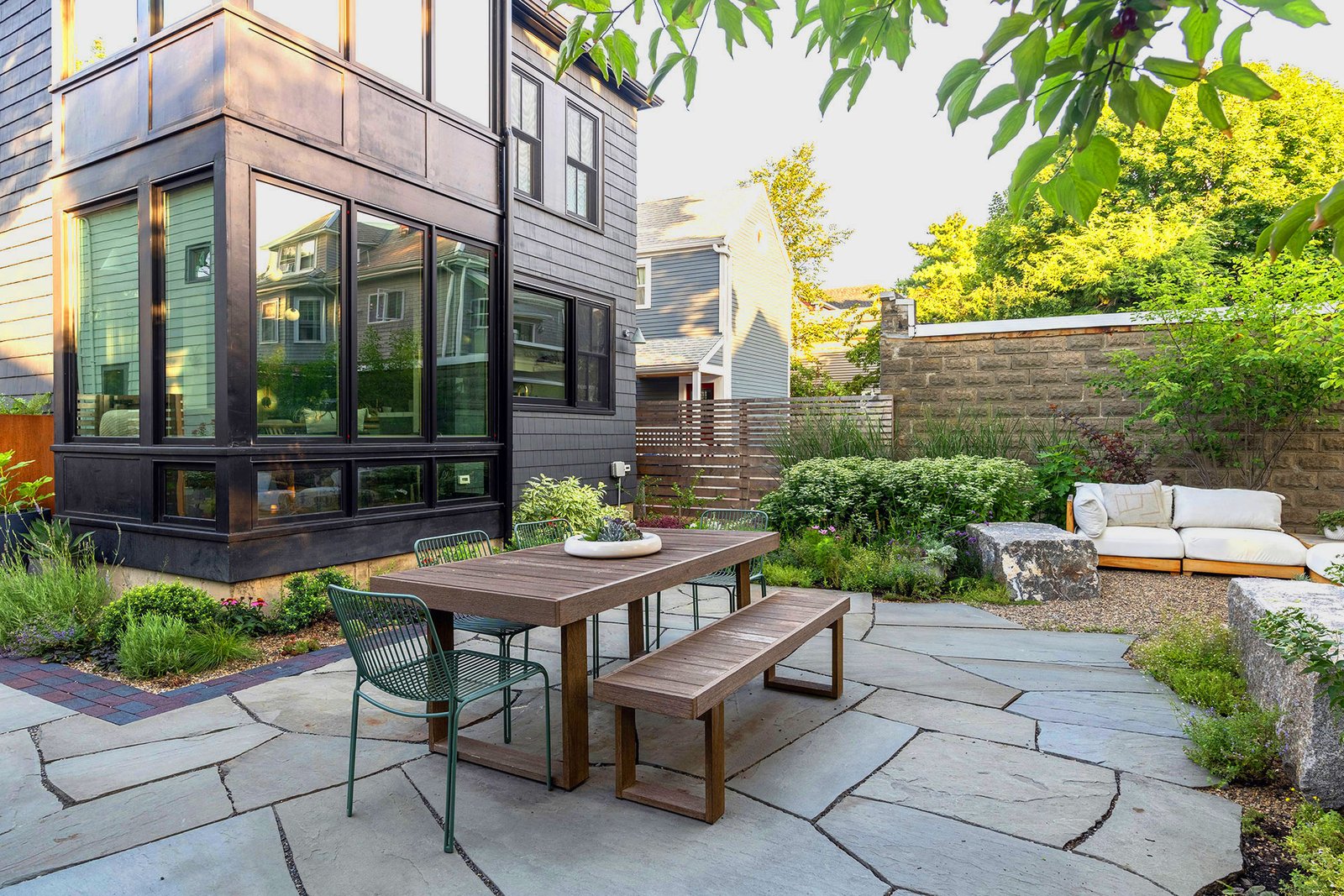 Cambridge, MA - Irregular stone patio with modern furnishings defines this urban backyard terrace, creating a chic outdoor lounge that maximizes space and privacy in city gardens.