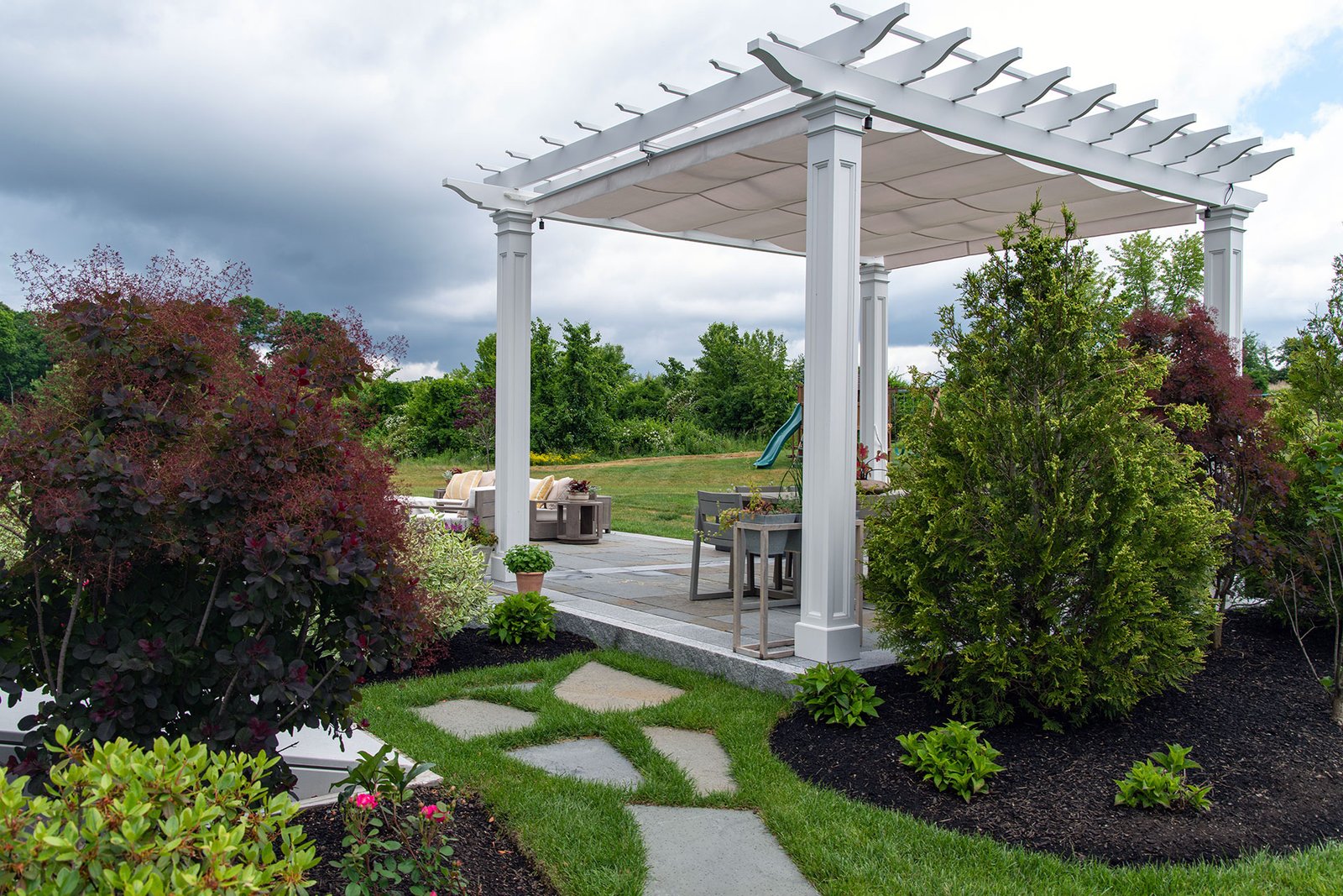 Low-maintenance vinyl pavilion with retractable canopy offers flexible shade and weather protection, ideal for garden patios and seasonal outdoor living.