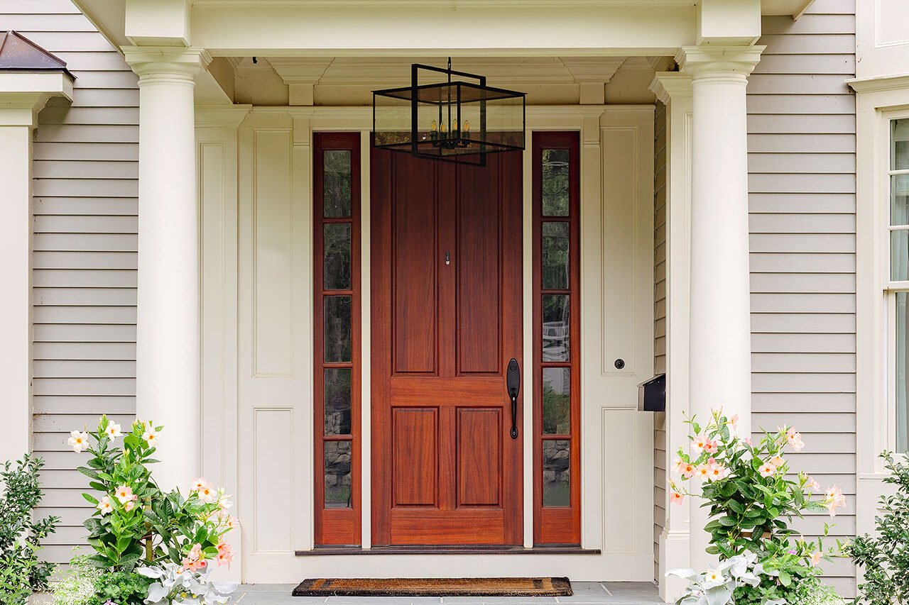Paired urns filled with flowering annuals reinforce the symmetry of a formal colonial entry and allow for easy summer color changes.