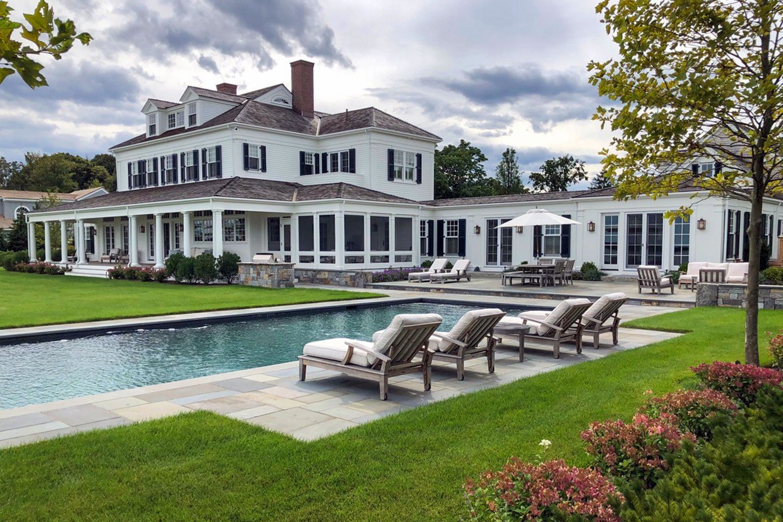 Residential landscape design in Duxbury, Massachusetts featuring a formal lap pool, open lawn, and cut-stone coping inspired by traditional New England coastal properties.