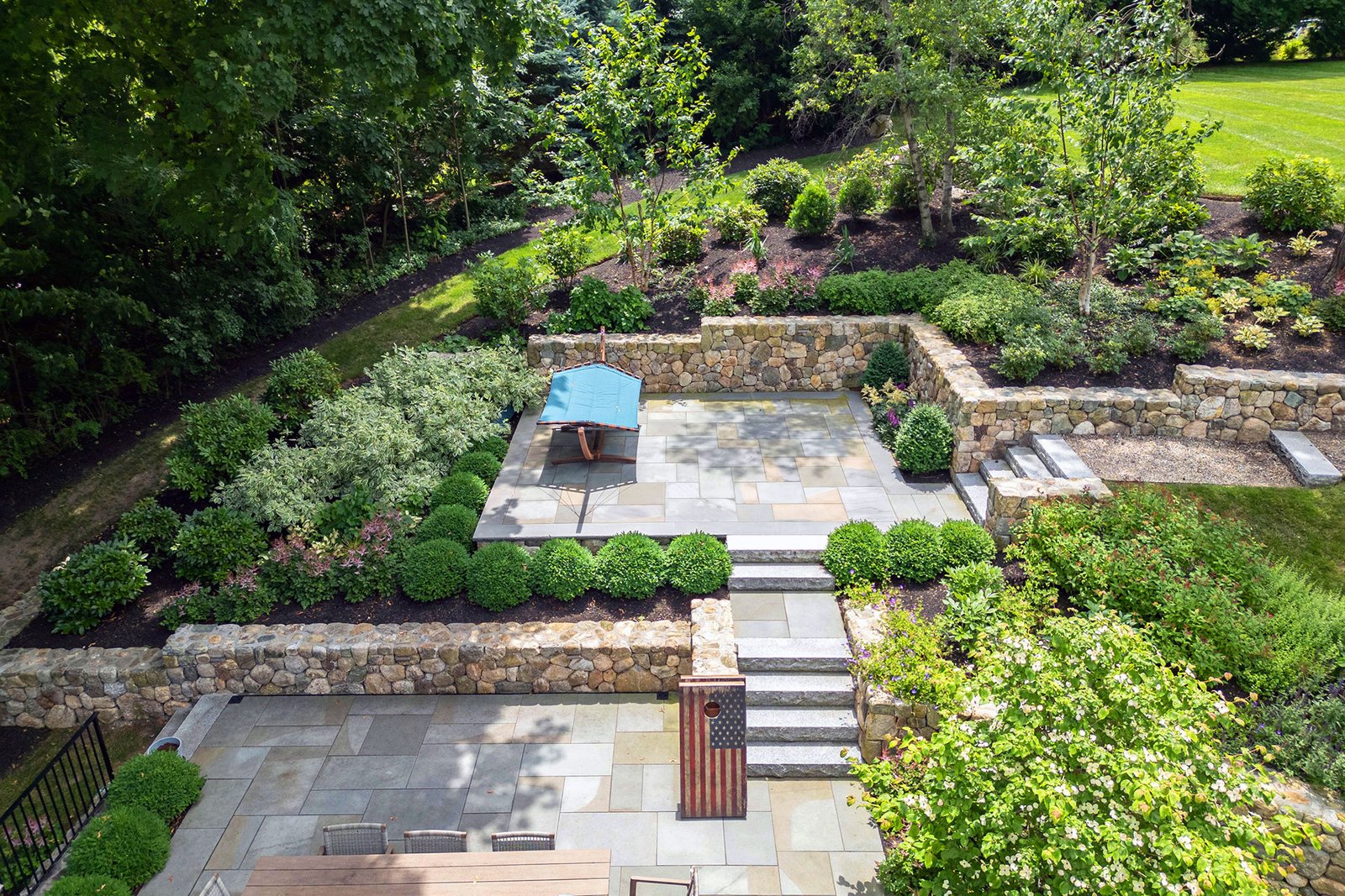 Lincoln, MA - Boxwood borders frame stone-walled terraces, layering evergreen structure with planting to define outdoor rooms and manage elevation changes.