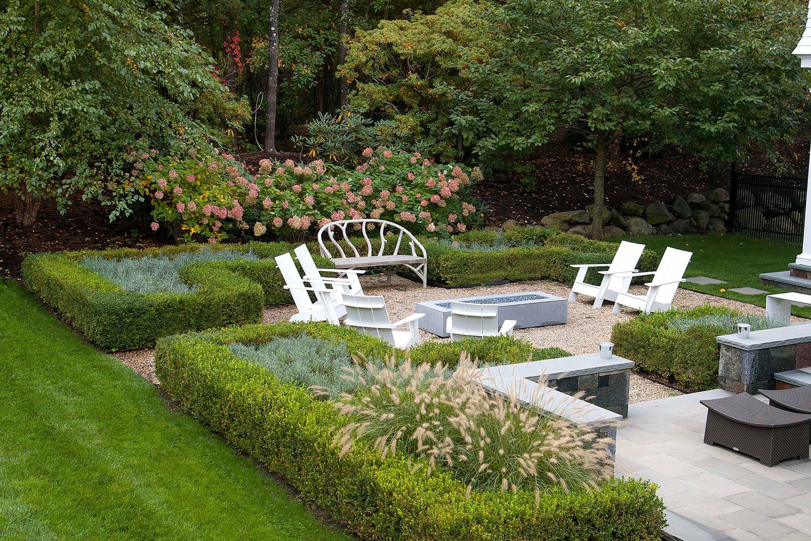 Weston, MA - Clipped boxwood hedges define this garden room in Weston, MA, framing a gravel patio and fire pit while adding year-round structure, privacy, and a refined sense of enclosure for outdoor living.
