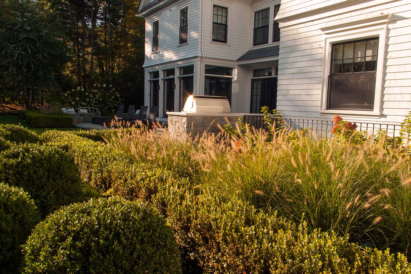 Weston, MA - Mixed shrubs and ornamental grasses frame this backyard terrace, blending movement, seasonal color, and soft screening to enhance outdoor living areas.