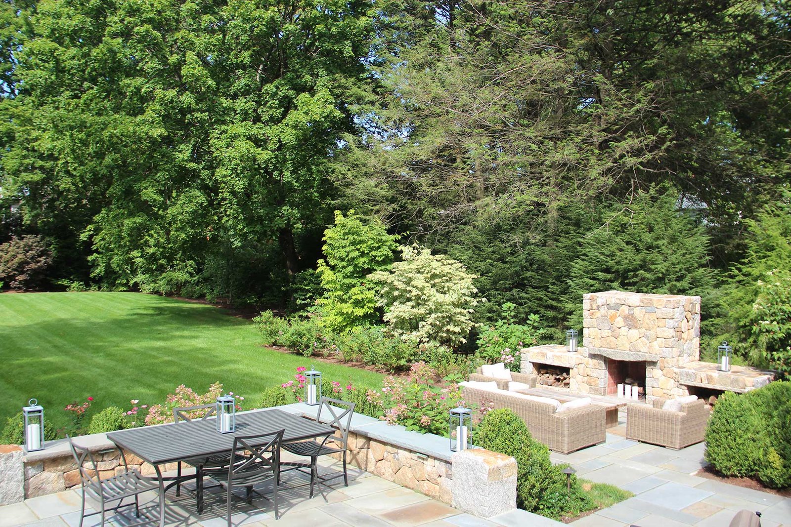 Newton Center backyard with stone patio, fireplace, and dining area