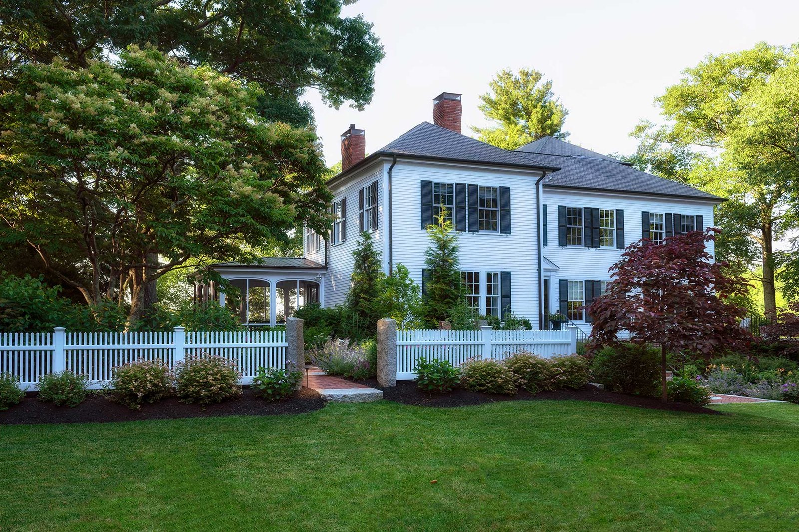 Lincoln front yard with white picket fence, brick walkway, and new foundation plantings
