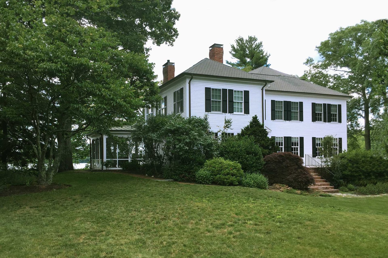 Lincoln front yard with mature shrubs and sloped lawn before landscape renovation