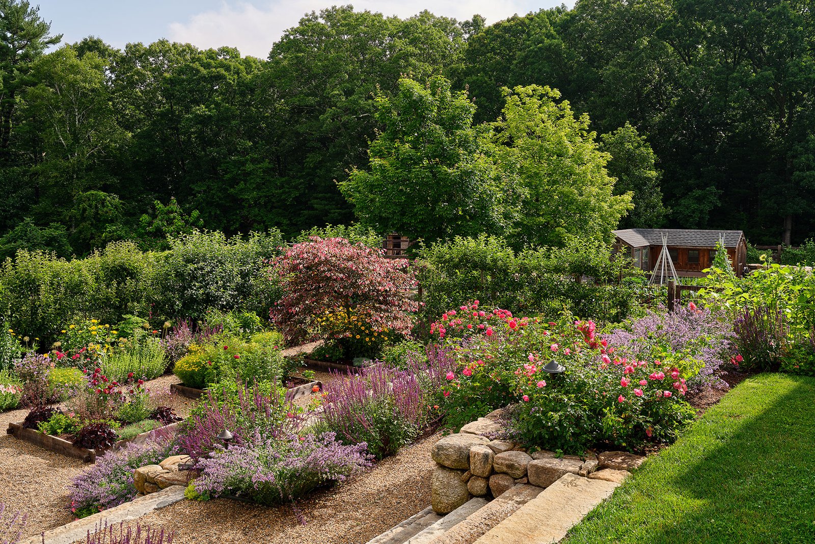 Flowering perennials mixed with vegetables attract pollinators and add seasonal interest to this New England garden.