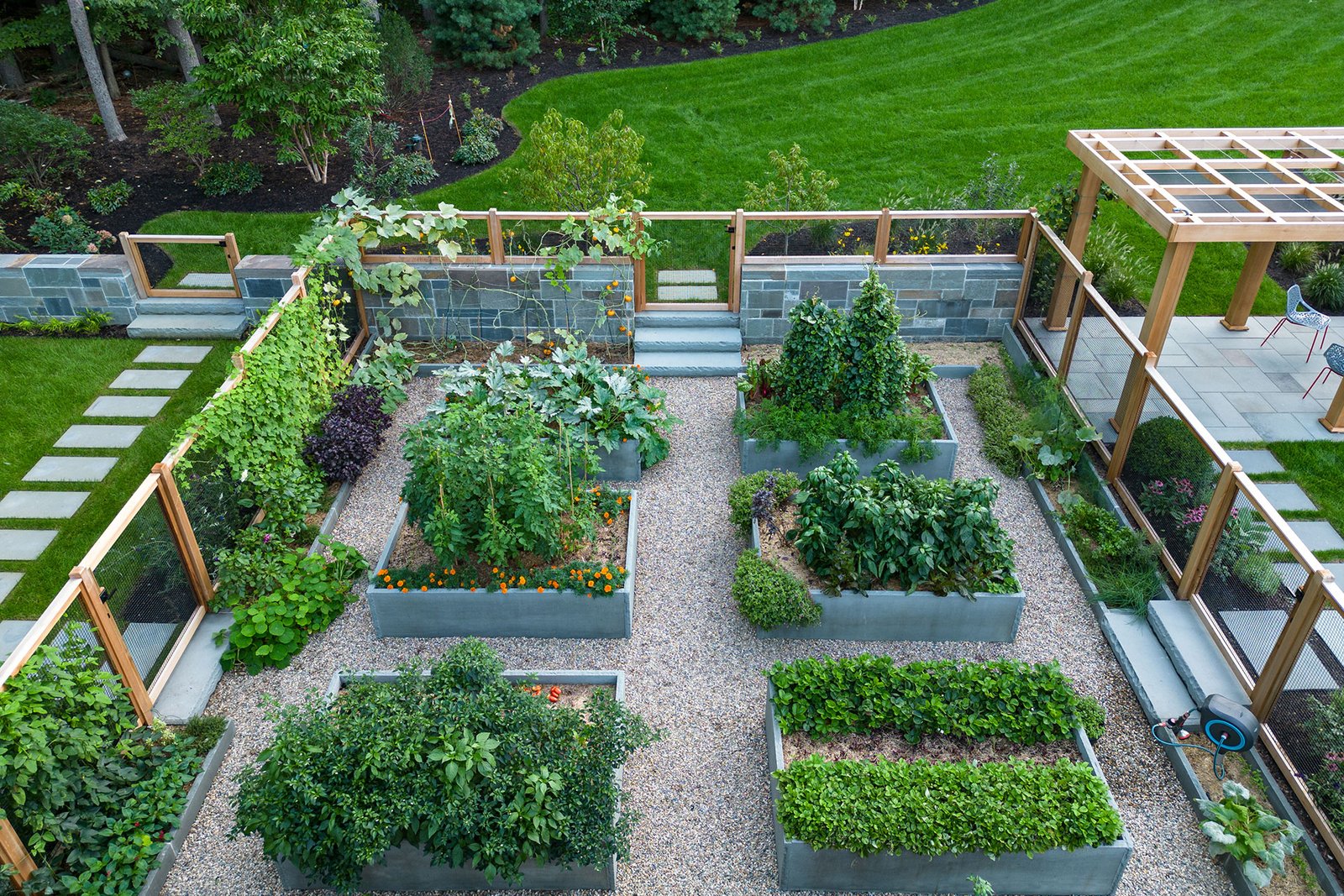 Raised vegetable beds set against stone walls improve soil control and heat retention, creating a durable garden layout well suited to Boston’s variable climate.