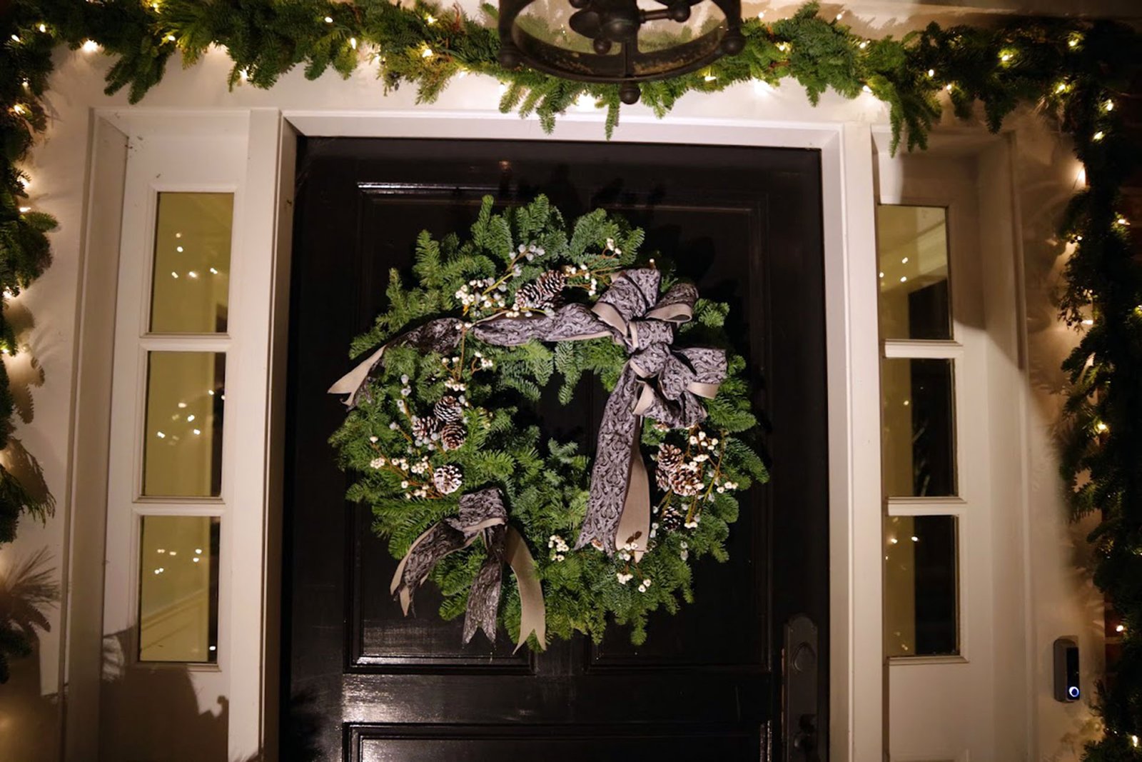 Boston entryway with a black front door decorated with an evergreen wreath and matching holiday garland.
