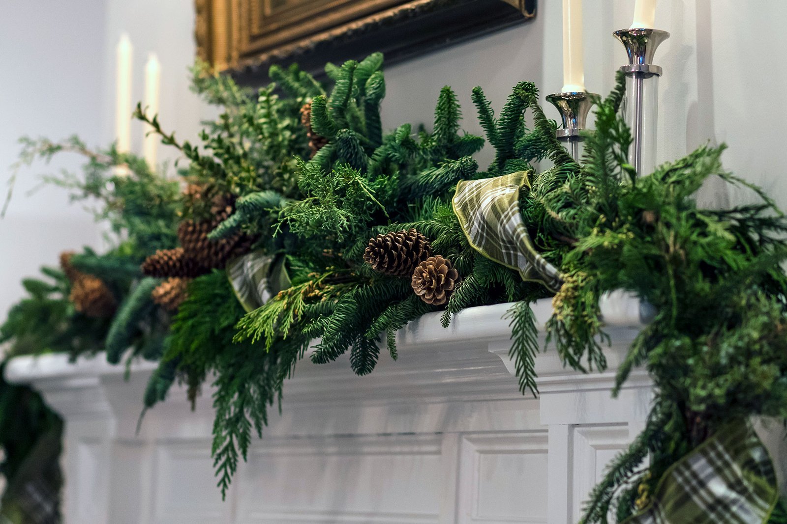 Holiday mantel decorated with lush greenery and elegant blue and silver ribbon accents.