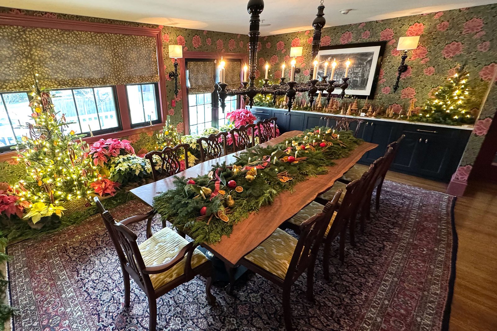 Brookline holiday dining table decorated with an evergreen garland centerpiece, candles, and seasonal greenery.
